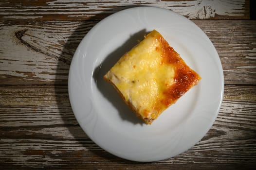 A tantalizing slice of homemade cheese lasagna rests elegantly on a white plate, inviting diners to savor its rich layers and warm flavors. Ideal for a comforting dinner.