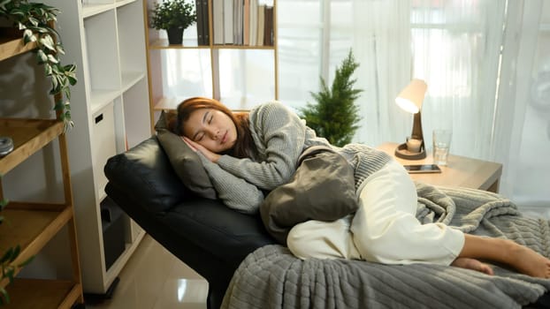 Young woman napping comfortably on a recliner in a cozy living room.