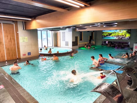 Glazov, Russia - February 16, 2025: Families and children play and relax in the indoor pool at a water park in Glazov, enjoying warm water and vibrant surroundings.