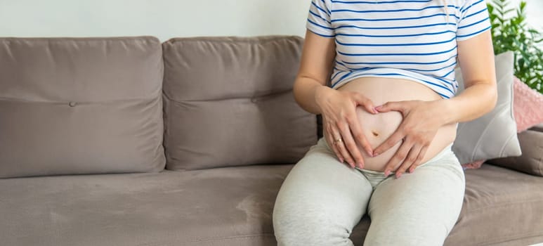 Pregnant woman hands heart belly. Selective focus. Love.