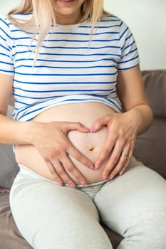 Pregnant woman hands heart belly. Selective focus. Love.