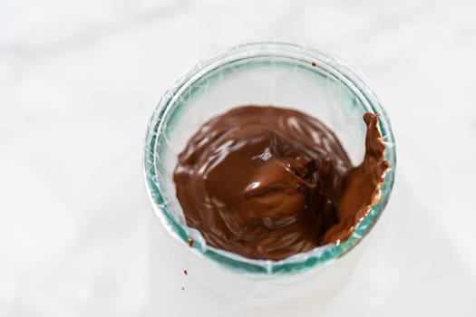 Melted Chocolate in Glass Bowl Description: Overhead view of smooth, melted chocolate in a glass bowl, ready for transferring into piping bags for the Chocolate Royal Icing.