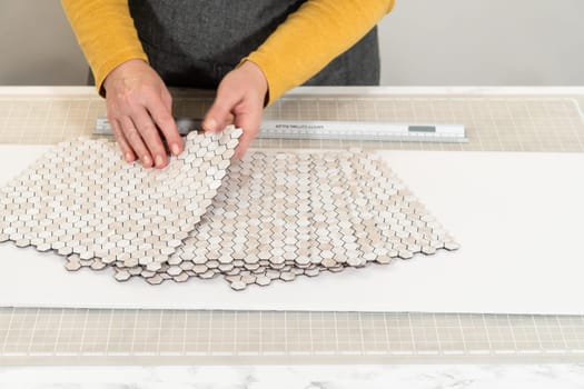 In the process of mounting peel and stick mosaic tiles onto a foam board, perfect for enhancing a food photography studio's aesthetic.