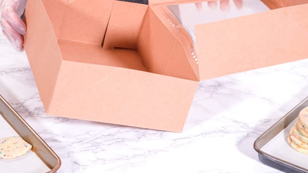 The sugar cookies, filled with sprinkles mixed into the dough, are carefully arranged with meticulous precision into a rustic brown paper box.