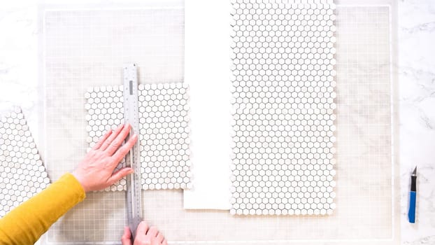 Flat lay. In the process of mounting peel and stick mosaic tiles onto a foam board, perfect for enhancing a food photography studio's aesthetic.