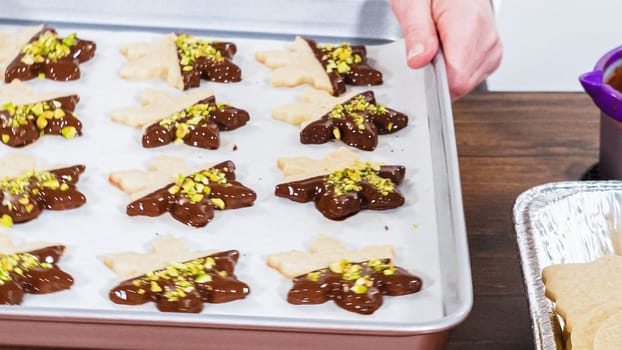 Crafting star-shaped holiday cookies dipped in chocolate and sprinkled with variety of toppings.