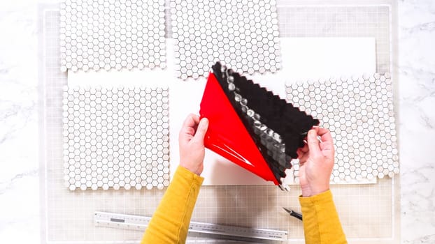 Flat lay. In the process of mounting peel and stick mosaic tiles onto a foam board, perfect for enhancing a food photography studio's aesthetic.