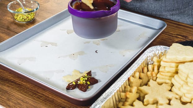 Crafting star-shaped holiday cookies dipped in chocolate and sprinkled with variety of toppings.