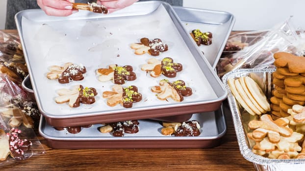 Carefully packaging Christmas cutout cookies, half-dipped in chocolate and presented in clear cellophane wrapping, perfect for festive gifting.