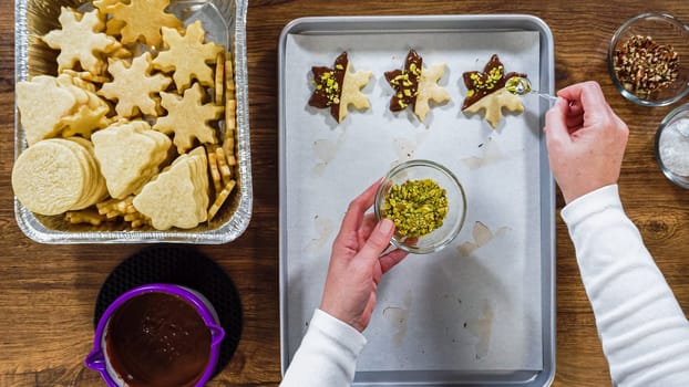 Flat lay. Creating snowflake-shaped cutout sugar cookies, dipped in chocolate, and adorned with different toppings.