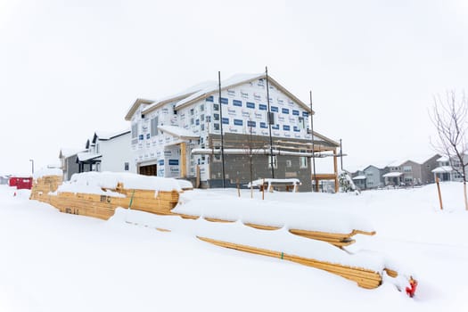 Castle Rock, Colorado, USA-March 14, 2024-Snow blankets the ground at a residential construction site where unfinished homes stand stark against the white landscape, their progress paused by winter's embrace