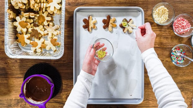 Flat lay. Creating snowflake-shaped cutout sugar cookies, dipped in chocolate, and adorned with different toppings.