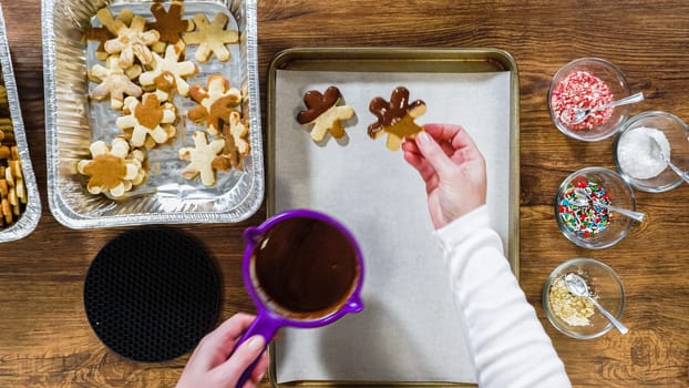 Flat lay. Creating snowflake-shaped cutout sugar cookies, dipped in chocolate, and adorned with different toppings.