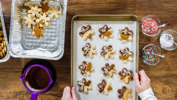Flat lay. Creating snowflake-shaped cutout sugar cookies, dipped in chocolate, and adorned with different toppings.