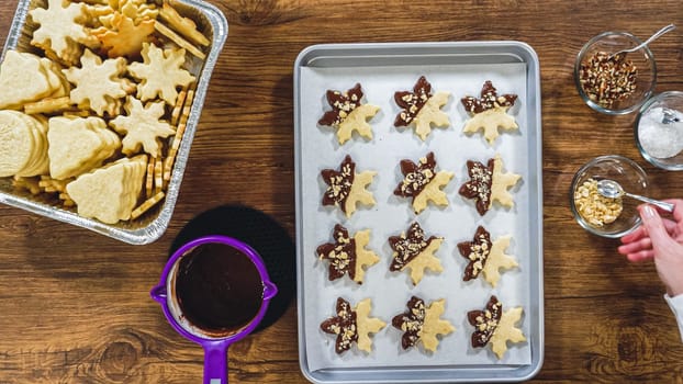Flat lay. Creating snowflake-shaped cutout sugar cookies, dipped in chocolate, and adorned with different toppings.