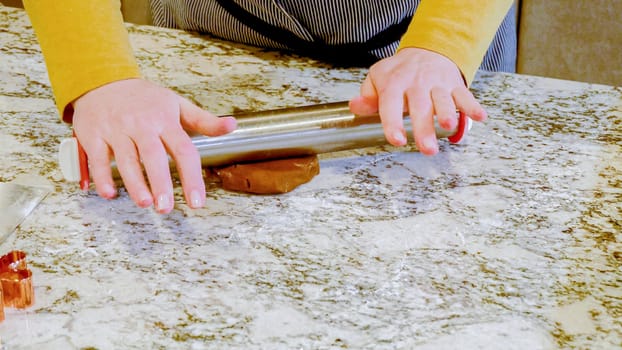 Using an adjustable rolling pin to roll out gingerbread cookie dough on the elegant marble counter in a modern kitchen, getting ready for festive holiday baking.