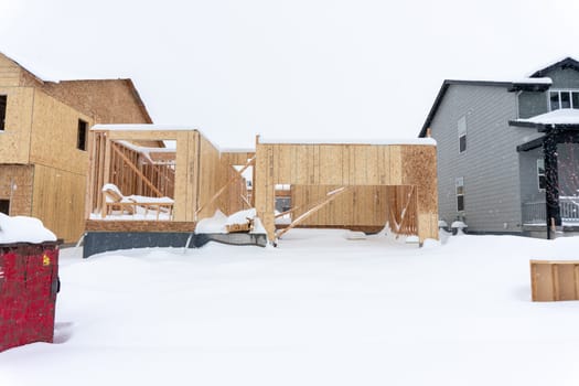 Castle Rock, Colorado, USA-March 14, 2024-Snow blankets the ground at a residential construction site where unfinished homes stand stark against the white landscape, their progress paused by winter's embrace