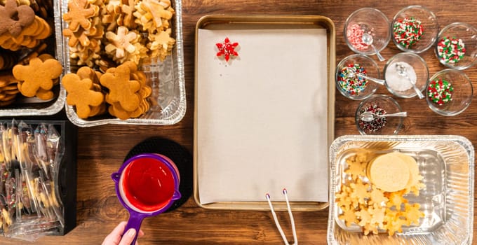 Vivid red star-shaped cookies, generously iced and speckled with green and white holiday sprinkles, freshly prepared and laid out to dry.