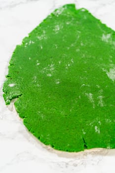 An overhead perspective of smoothly rolled green gingerbread dough spread out on a marble surface, showcasing the vibrant green color of the Green Gingerbread Cookies dough, ready to be shaped.