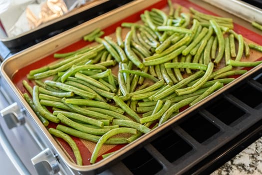 Watch as fresh green beans are beautifully roasted to perfection on a baking sheet with a silicone mat, adding a burst of flavor to your meal.