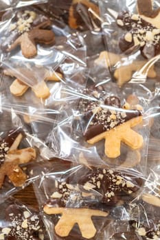 Carefully packaging Christmas cutout cookies, half-dipped in chocolate and presented in clear cellophane wrapping, perfect for festive gifting.