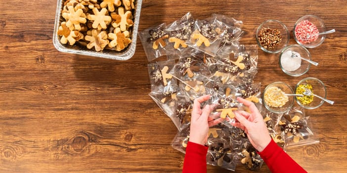 Carefully packaging Christmas cutout cookies, half-dipped in chocolate and presented in clear cellophane wrapping, perfect for festive gifting.