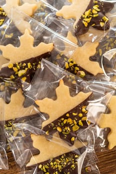 Carefully packaging Christmas cutout cookies, half-dipped in chocolate and presented in clear cellophane wrapping, perfect for festive gifting.
