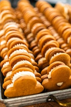 Making gingerbread man cookie sandwiches filled with eggnog buttercream, arrayed on a rustic wooden table, ideal for heartfelt Christmas gifting.