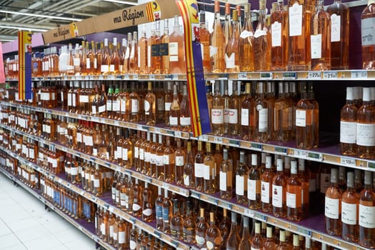 Nice, France - June 13, 2023: Lots of local traditional rose wine bottles on a shelf of a local store