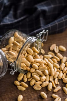 Roasted salted peanuts in jar on a wooden table.