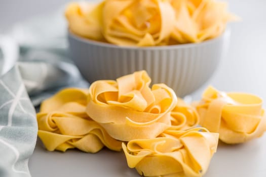 Italian pasta tagliatelle. Uncooked noodle pasta on a gray background.