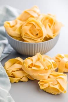 Italian pasta tagliatelle. Uncooked noodle pasta on a gray background.