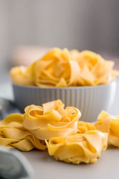 Italian pasta tagliatelle. Uncooked noodle pasta on a gray background.