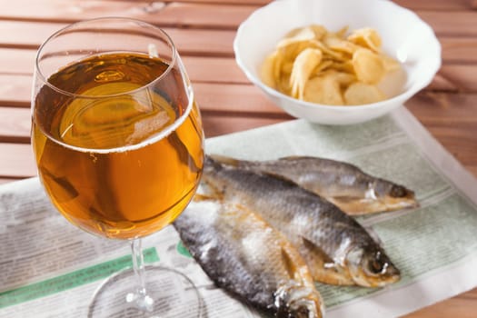 Lager beer and dry fish, garlic and chips on wooden table, top view