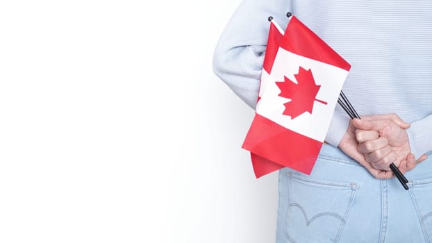 Unrecognized girl student in white blue shirt holding small Canadian flag over gray background, Canada day, holiday, vote, immigration, tax, copy space.