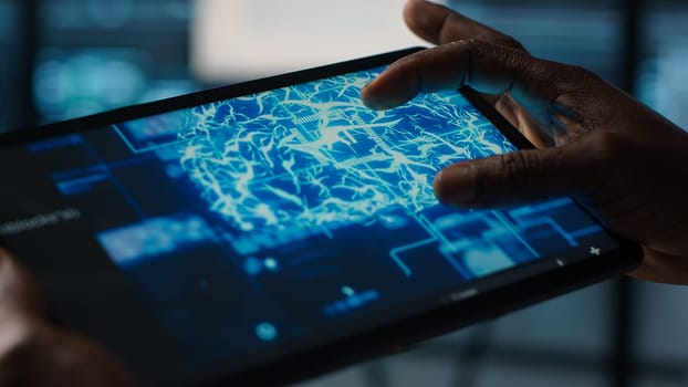 Close up of computer scientist in data center uses AI on tablet, verifying compliance of racks. IT expert using artificial intelligence on device to optimize resource utilization, camera A