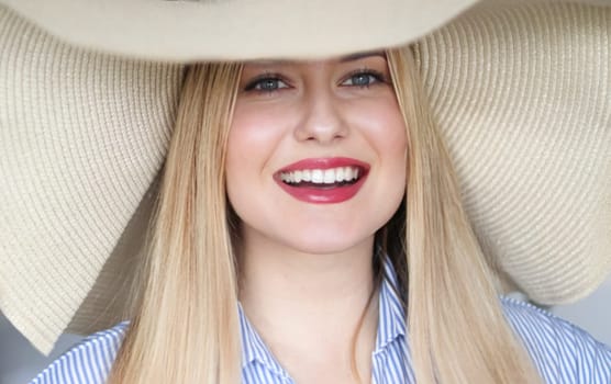 Woman, fashion and summer country charm, blonde beauty and elegance in wide brimmed beach hat. Feminine allure, timeless style and graceful glow. Smile, straw hat and blue striped blouse, natural lighting and effortless charm, fashion look idea