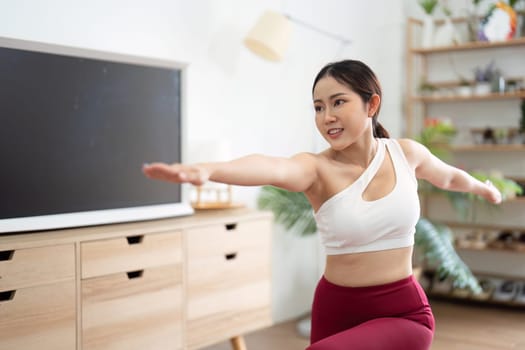 Focusing on her posture, a woman practices yoga, emphasizing both physical strength and mental clarity in a calming environment.