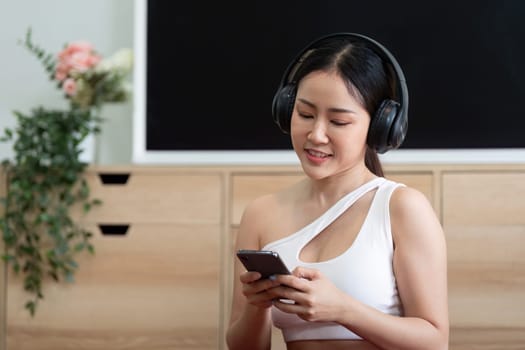 A woman engages with her smartphone while wearing headphones, blending technology with fitness in her daily routine.