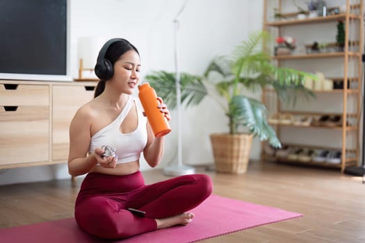 After a productive yoga session, a woman hydrates with her water bottle, emphasizing the importance of wellness and self-care.