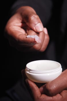 Hands applying petroleum jelly closeup .