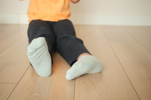 Young child in orange shirt sits on floor, engaged in playtime activities.