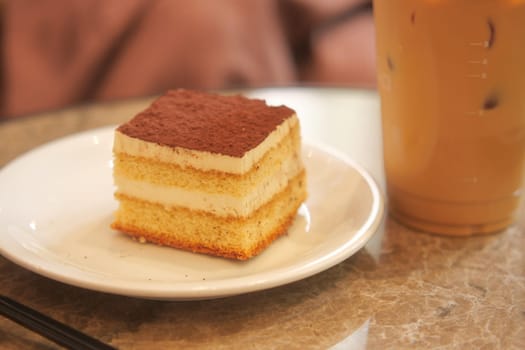 A slice of cake and iced coffee are enjoyed at a cafe table.