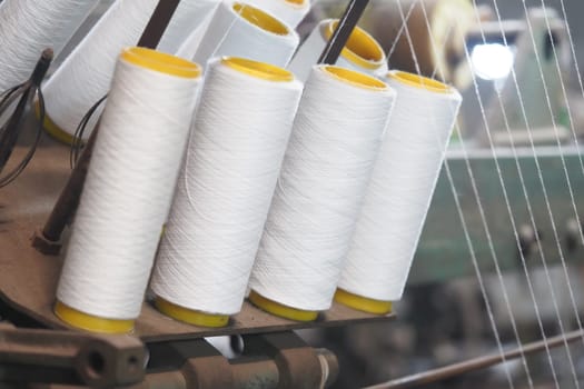 White thread spools on a textile machine highlight craftsmanship.