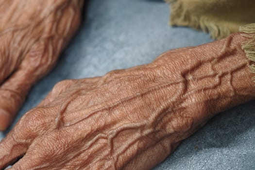 Hands of an elder displaying deep wrinkles and lines in natural light.