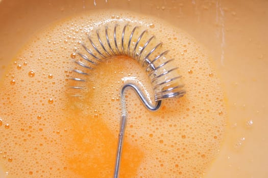 Eggs are being whisked vigorously in a bowl for preparation.