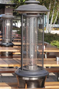 Elegant heating lanterns stand ready, warming outdoor tables during evening.