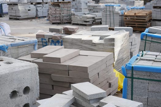 Workers organize concrete blocks at a busy construction site.