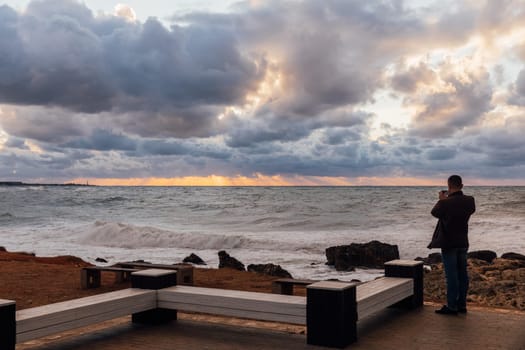 A man shoots a sea storm at sunset on his smartphone