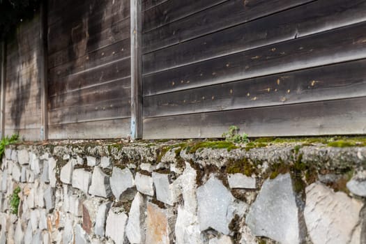 Rough texture wooden fence with old weathered stone basement. Texture background for design.
